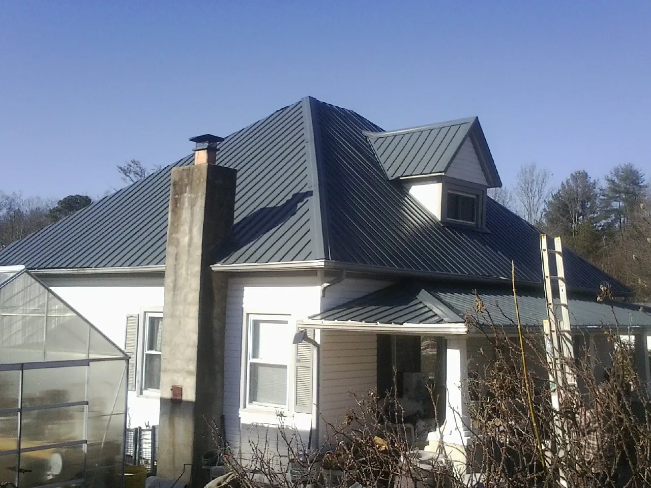 Dark blue standing seam metal roof on a white farmhouse with dormer — Slate & Tile Roof Repair by Roofing Brothers in Gordonville