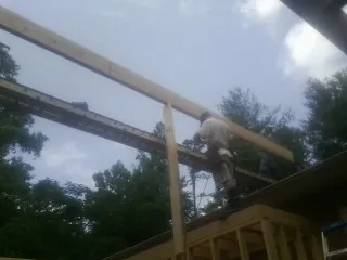 Carpenter setting a ridge beam over a new addition frame — Ice Dam Removal by Roofing Brothers in Gordonville