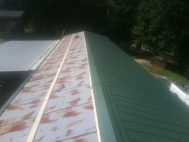 Old rusted panels beside newly installed green metal roofing — Wind Damage Roof Repair by Roofing Brothers in Gordonville