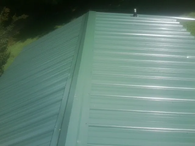 New green metal panels meeting at the ridge of a roof — Flat Roof Repair work by our crew in Gordonville