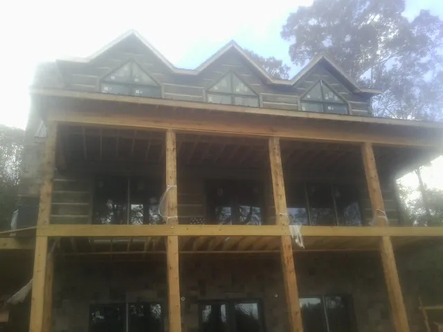 Dormers and porch framing on a large log home under construction — Roof Coating work by our crew in Gordonville