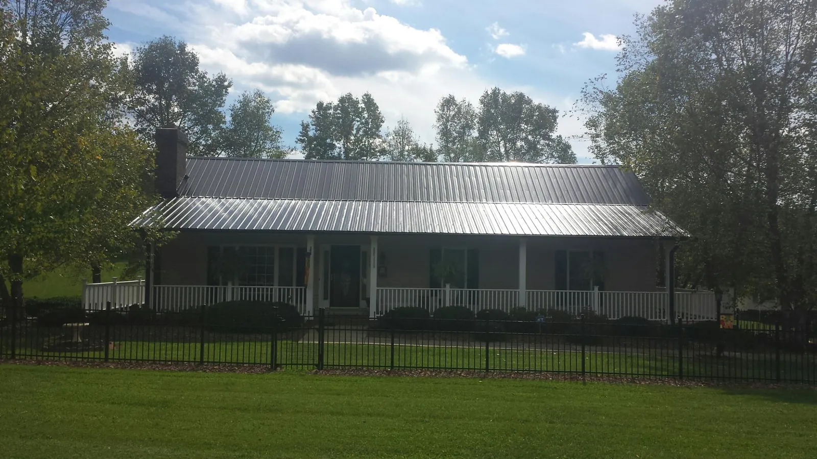 Gray metal roof on a brick ranch with a full width front porch — Gutter Guard Installation work by our crew in Gordonville