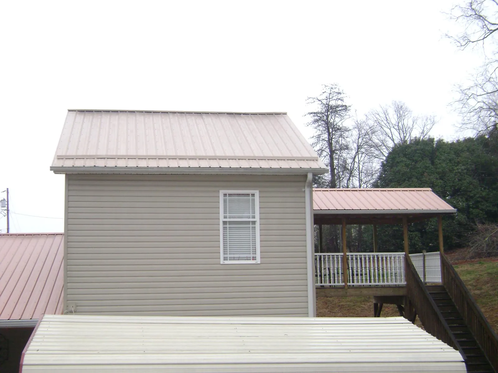 Tan metal roofs on a two story addition and attached porch, from a Roof Replacement job in Gordonville