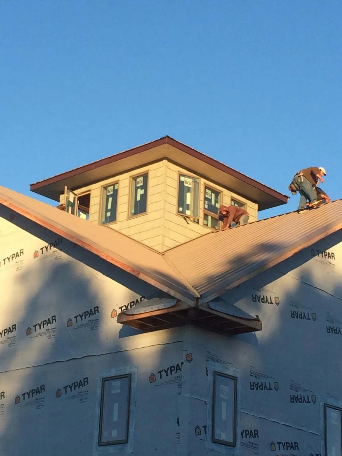 Roofers working around a rooftop cupola on a new metal roof at sunset — Roof Waterproofing in Gordonville by Roofing Brothers